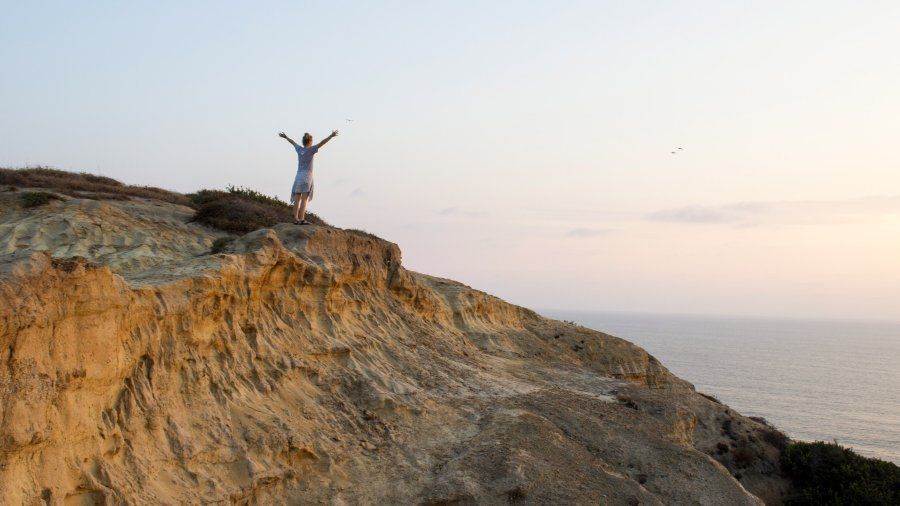 A 69 student spreads her arms and watches the sunset on the San Diego cliffside.