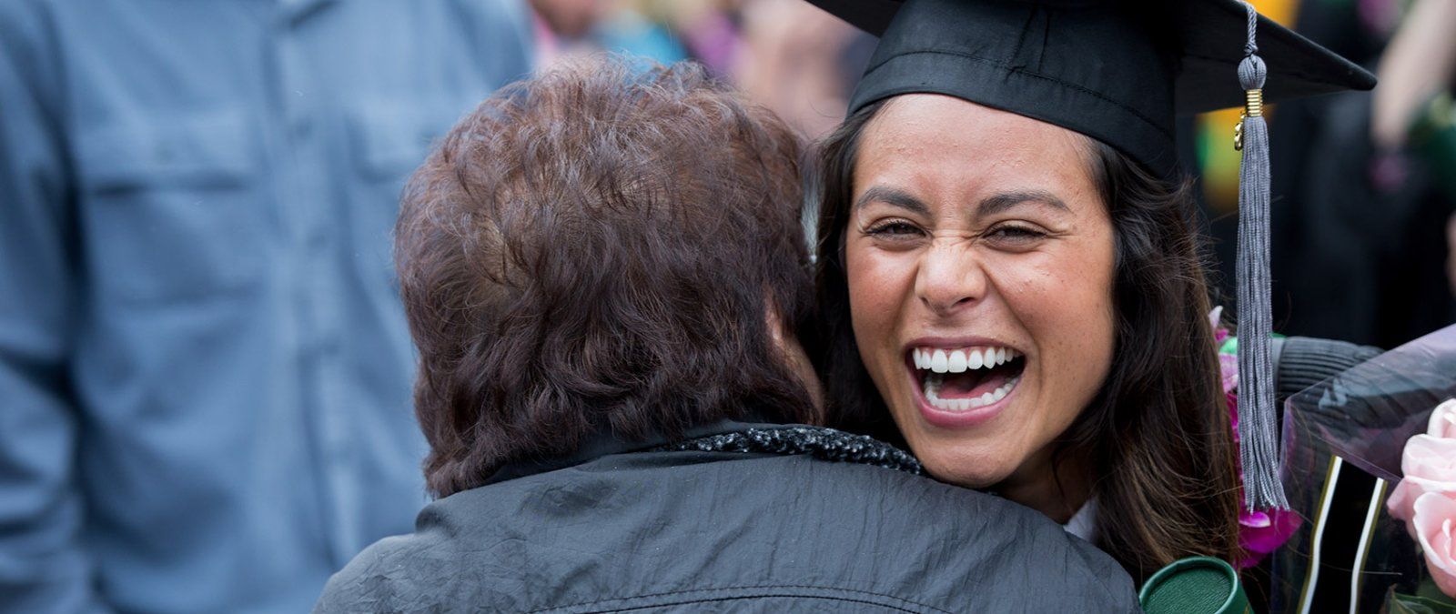 A 69 graduate student is embraced by a grandparent after commencement.